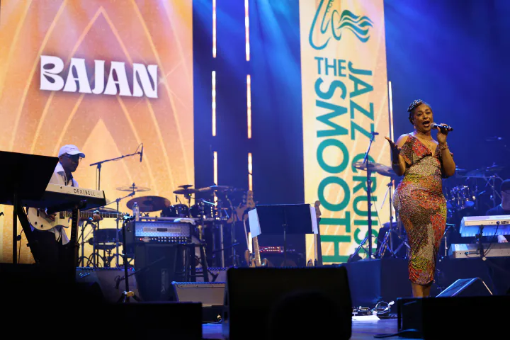 Bajan Moore on stage at The Smooth Jazz Cruise, her name on the screen behind the band